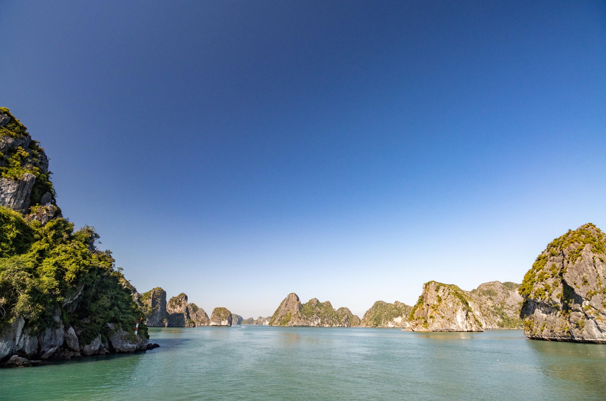 Ha Long Bay limestone karsts and cruise boat in emerald waters Vietnam